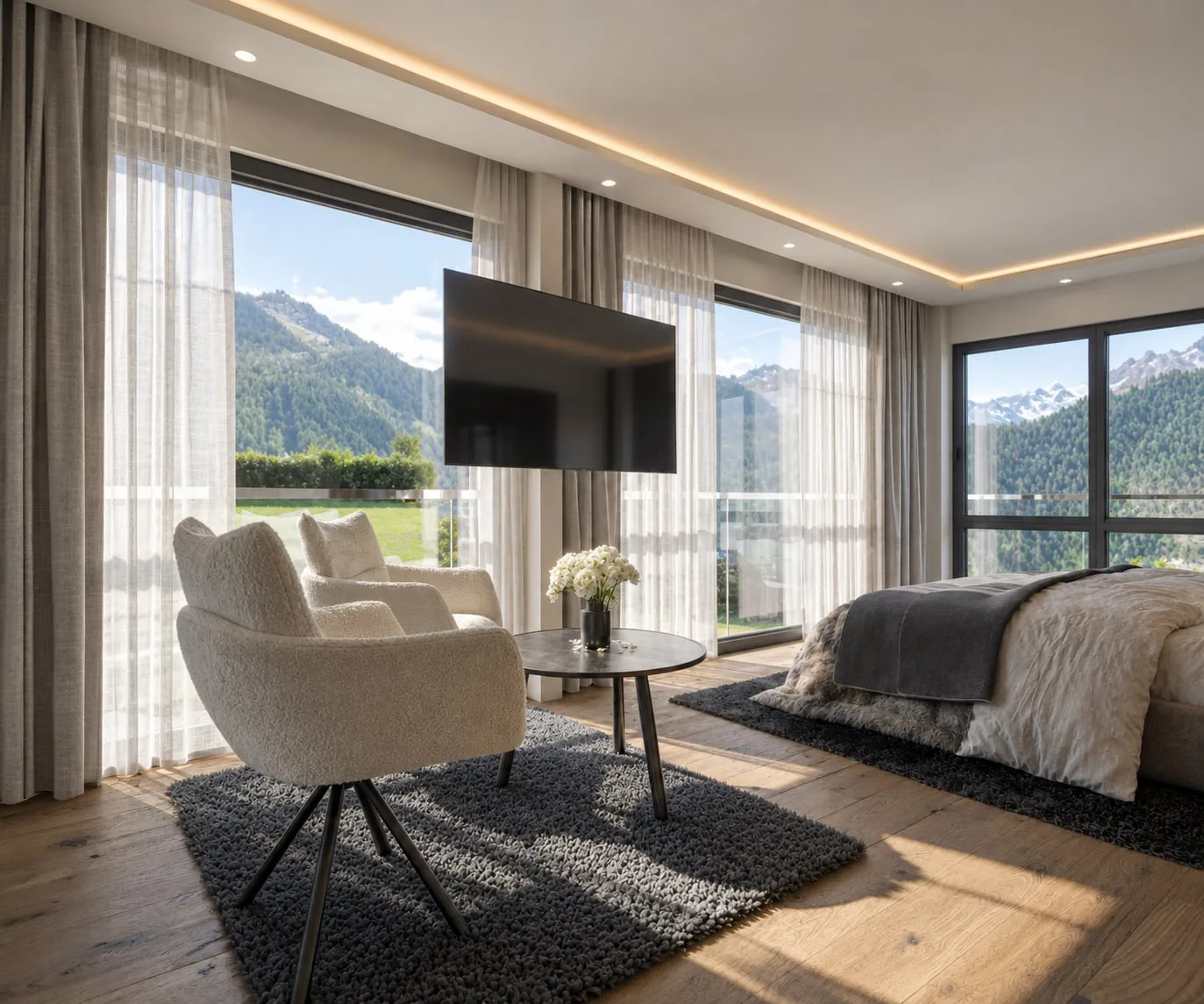 A bedroom and sitting corner in one room, wall-mounted screen, sheer curtains drawn back from a window looking out to the mountains