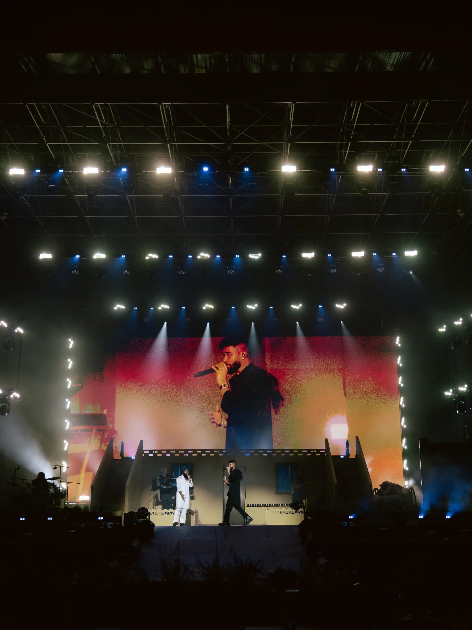 The artist on stage under white strip lighting at the Malta show