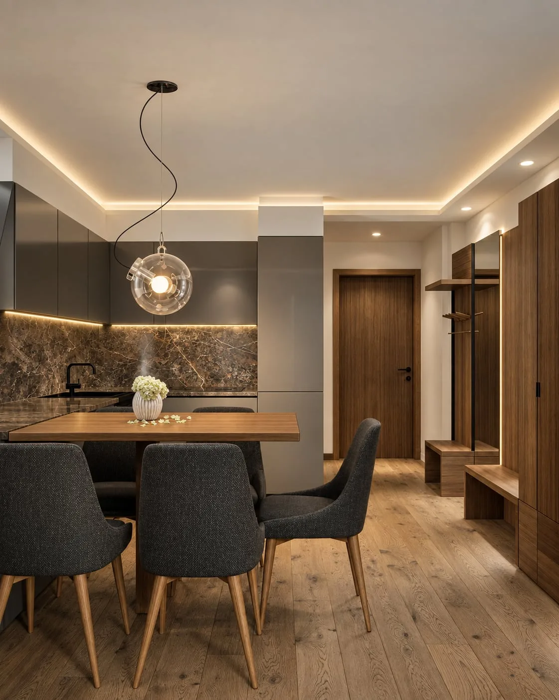 The kitchen and dining end of an apartment, dark stone splashback, a glass globe pendant over the table and the entrance hall behind