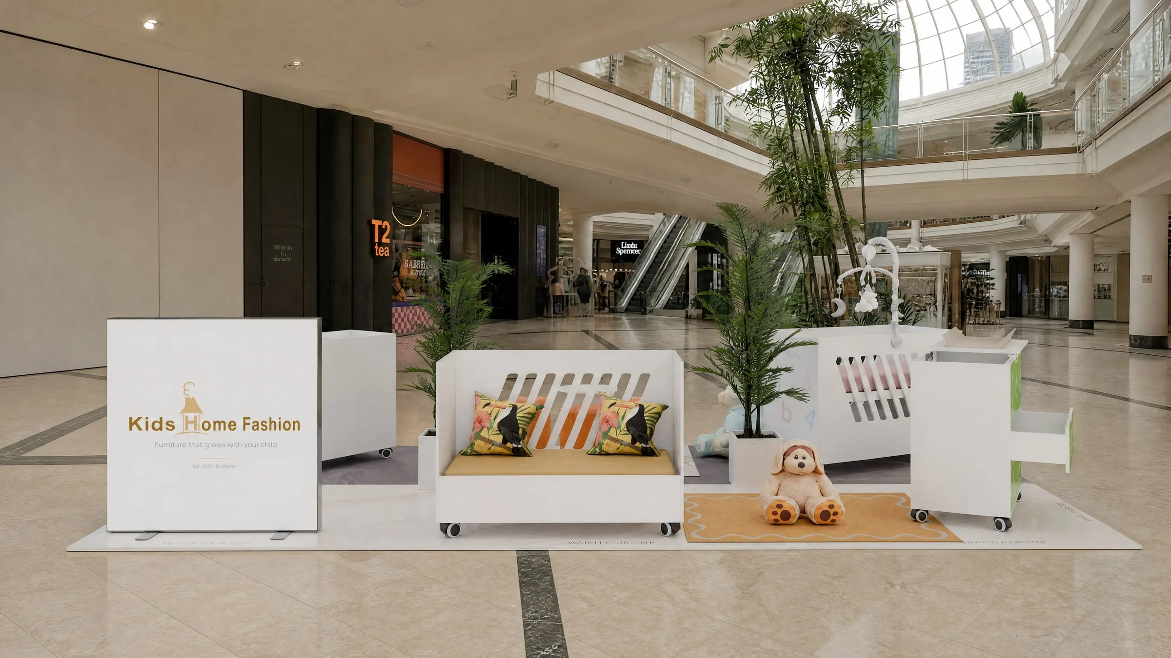 The kiosk seen along the mall, palms either side of a branded backdrop