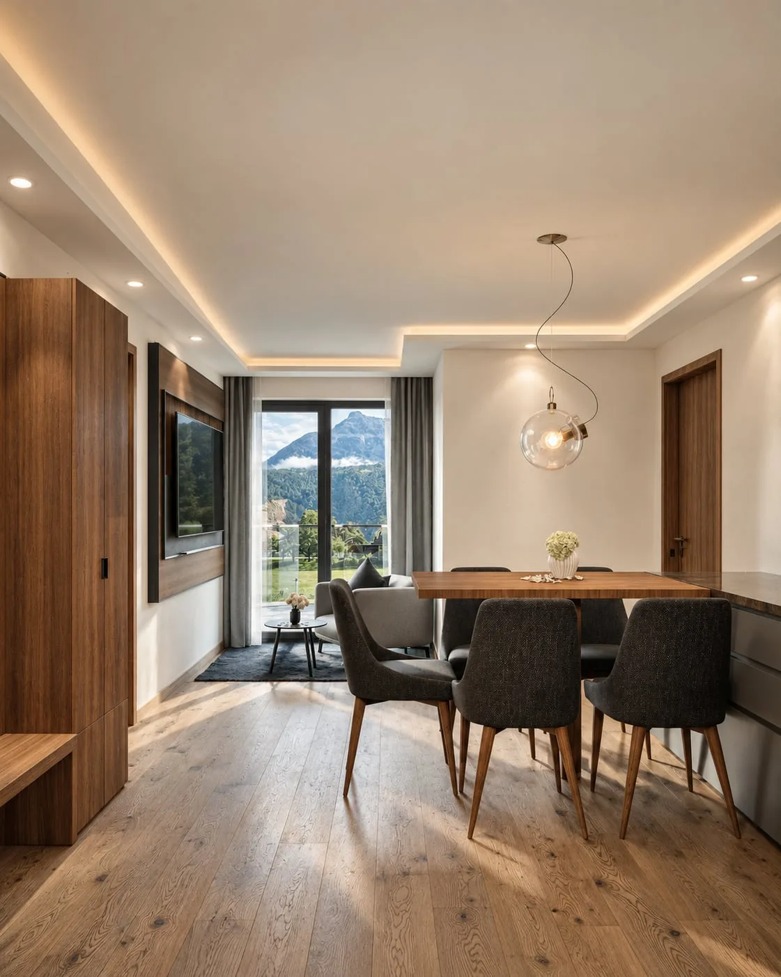A dining table under a globe pendant, the screen recessed into the timber wall opposite and the valley through the window