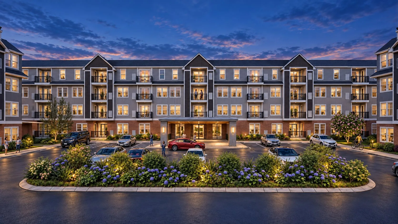 The courtyard at dusk with every window lit, the planted island and parked cars in shadow below